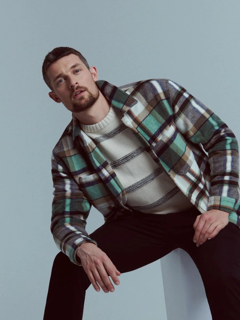 Layering for a brisk day, Wouter Peelen wears a checkered overshirt with a striped sweater by Reserved.