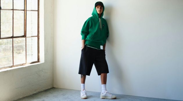 Romeo Beckham Rocks Sporty Style for PUMA x AMI Campaign Romeo Beckham sports a green hoodie, oversized shorts, and white leather sneakers for the PUMA x AMI campaign.