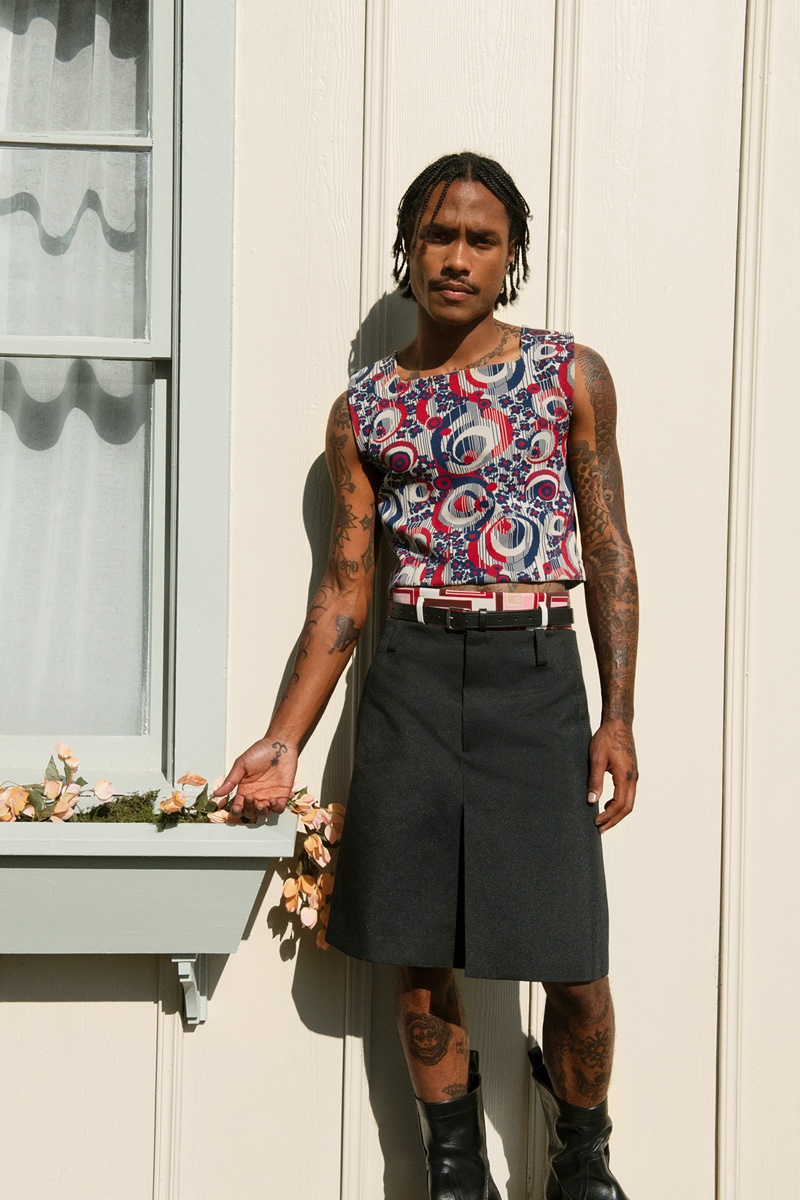 Making a bold style statement, Steve Lacy wears a Prada knit vest with a Burberry pleated skirt for Farfetch's spring-summer 2022 men's campaign.