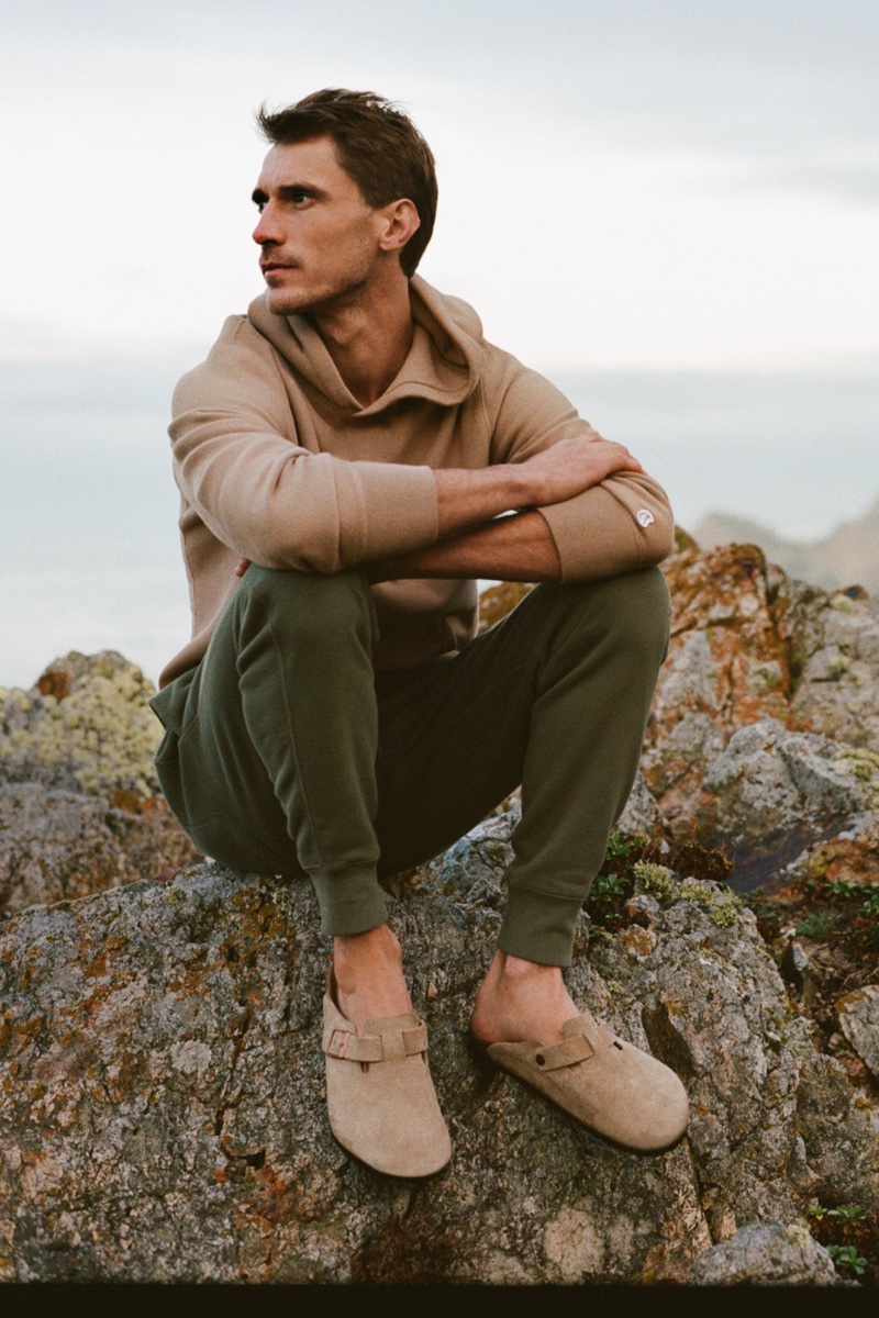 Taking a moment to relax, Clément Chabernaud wears a Todd Snyder + Champion sun-faded popover hoodie sweatshirt and sweatpants with Birkenstock Boston clogs. 