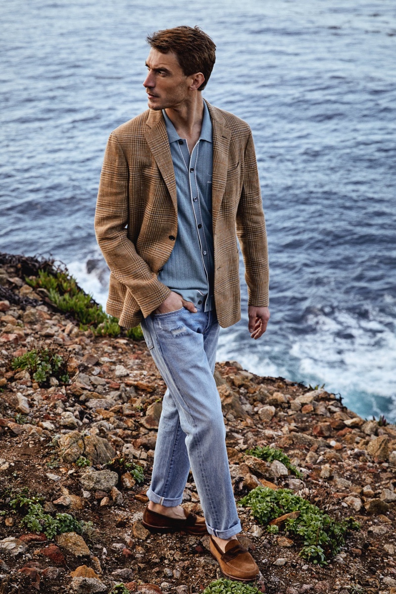 A chic vision, Clément Chabernaud models a Todd Snyder soft Italian sportcoat in brown glenplaid with a cotton-silk full placket polo, slim-fit selvedge jeans in a destroyed Broome wash, and Todd Snyder + Alden two-tone penny loafers.