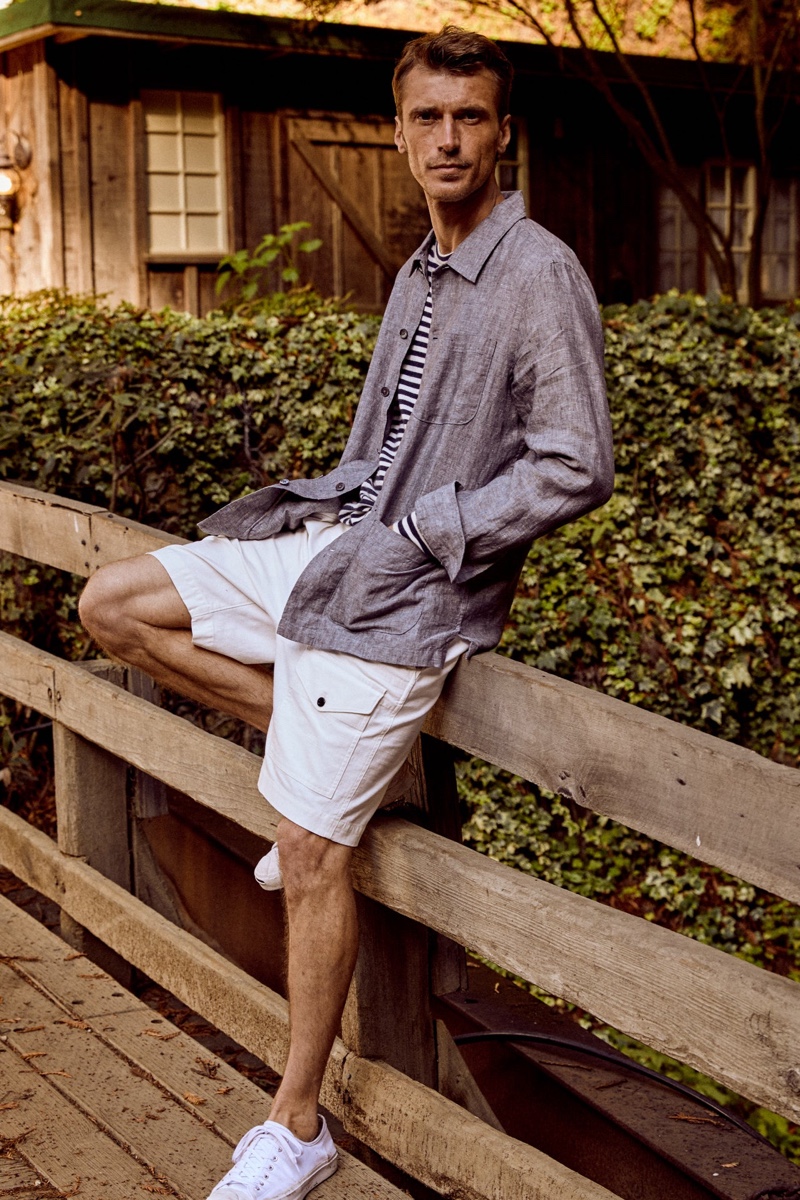 Embracing spring style from Todd Snyder, Clément Chabernaud wears an Italian linen chore shirt in blue with an Issued by: Japanese nautical striped tee, 9" Japanese utility shorts, and Converse Jack Purcell canvas sneakers.