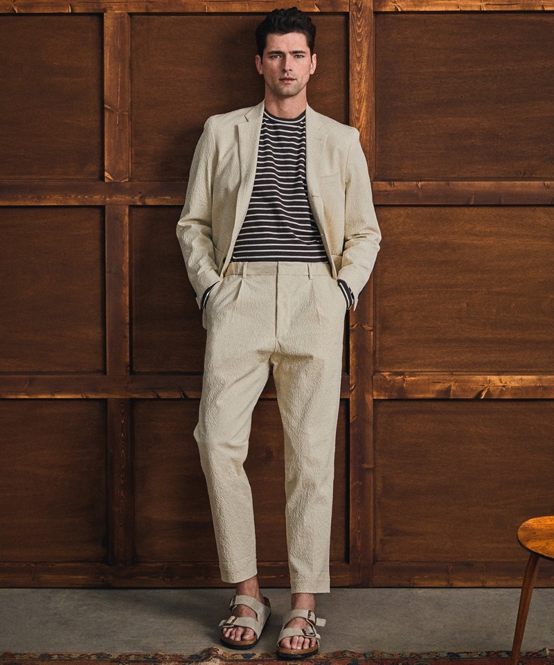 Inspiring in spring style from Todd Snyder, Sean O'Pry wears an Italian seersucker Traveler suit in stone with an Issued by: Japanese nautical striped tee in navy and Birkenstock Arizona suede sandals in taupe.