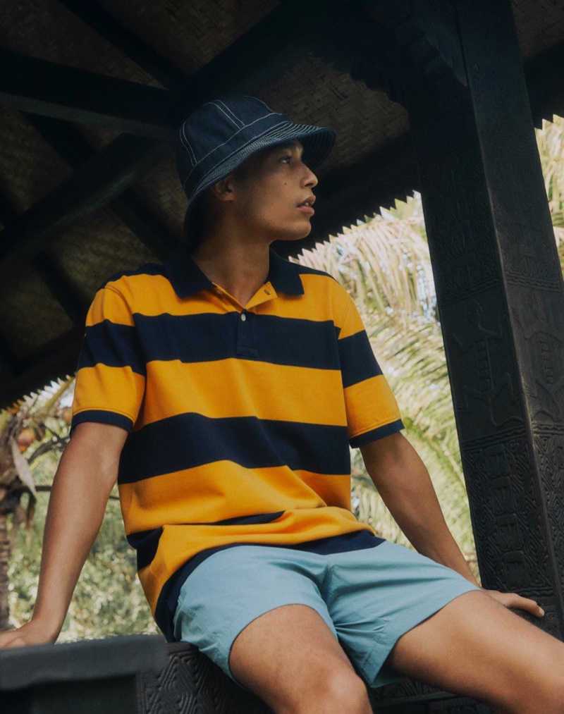 Luke Cousins wears a J.Crew striped piqué polo shirt with 6" tech dock shorts and a denim Wallace & Barnes bucket hat.