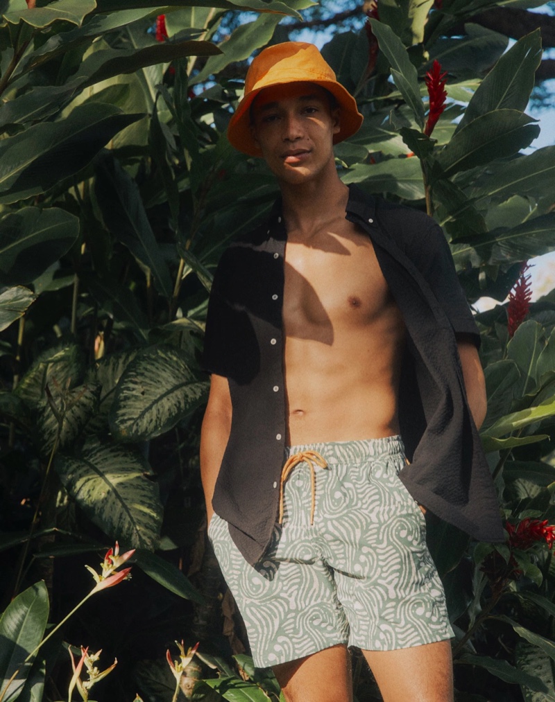 Embracing a vacation vibe, Luke Cousins wears J.Crew short-sleeve seersucker shirt with 6" stretch swim trunks in a batik print and a garment-dyed ripstop bucket hat.