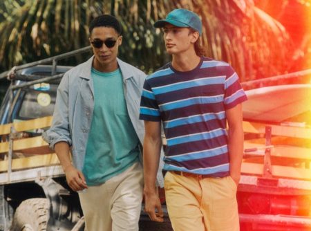 Left: Luke Cousins wears a J.Crew secret wash striped poplin shirt with a garment-dyed pocket t-shirt, drawstring pants, Bungalow sunglasses, and Birkenstock Arizona sandals. Right: James Turlington models a J.Crew striped pocket t-shirt, camp pants in yellow, a garment-dyed twill baseball cap, striped elastic webbing belt, and Adidas Gazelle suede sneakers.