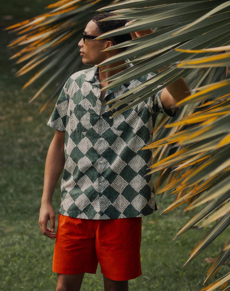 Making a case for prints, Luke Cousins rocks a short-sleeve square dot green camp-collar shirt with 7" red sustainable kayak shorts, and Grant sunglasses by J.Crew.