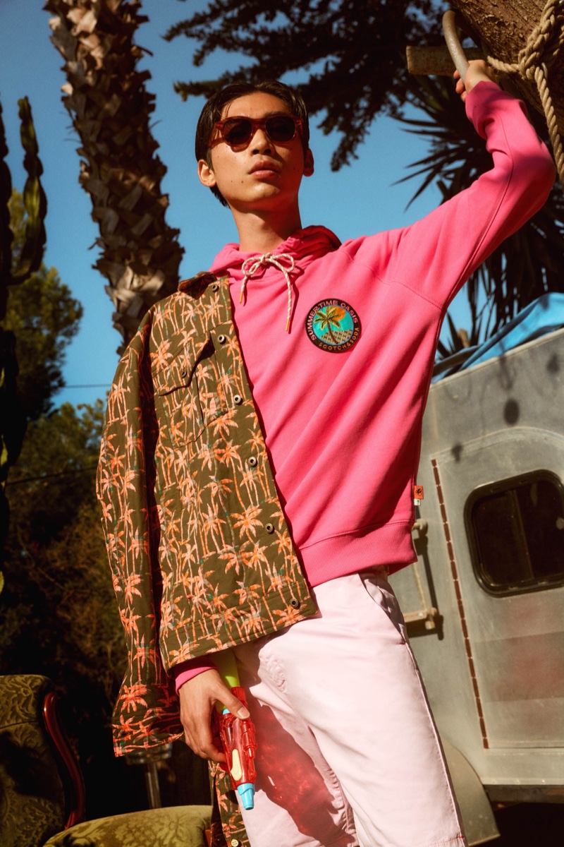 Hidetatsu Takeuchi is ready for summer in a palm tree print jacket, pink hoodie, and swim shorts from Scotch & Soda.