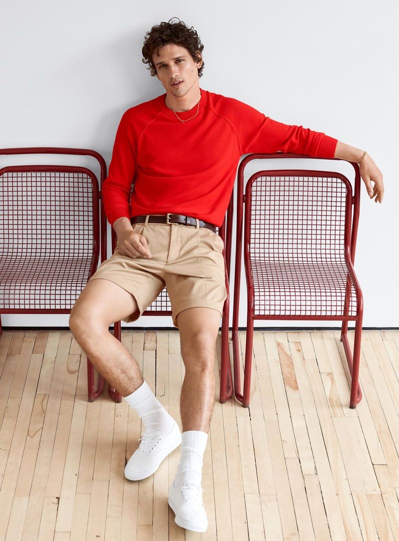 Connecting with Simons for spring, Simon Nessman wears a red pullover with khaki shorts and white sneakers.