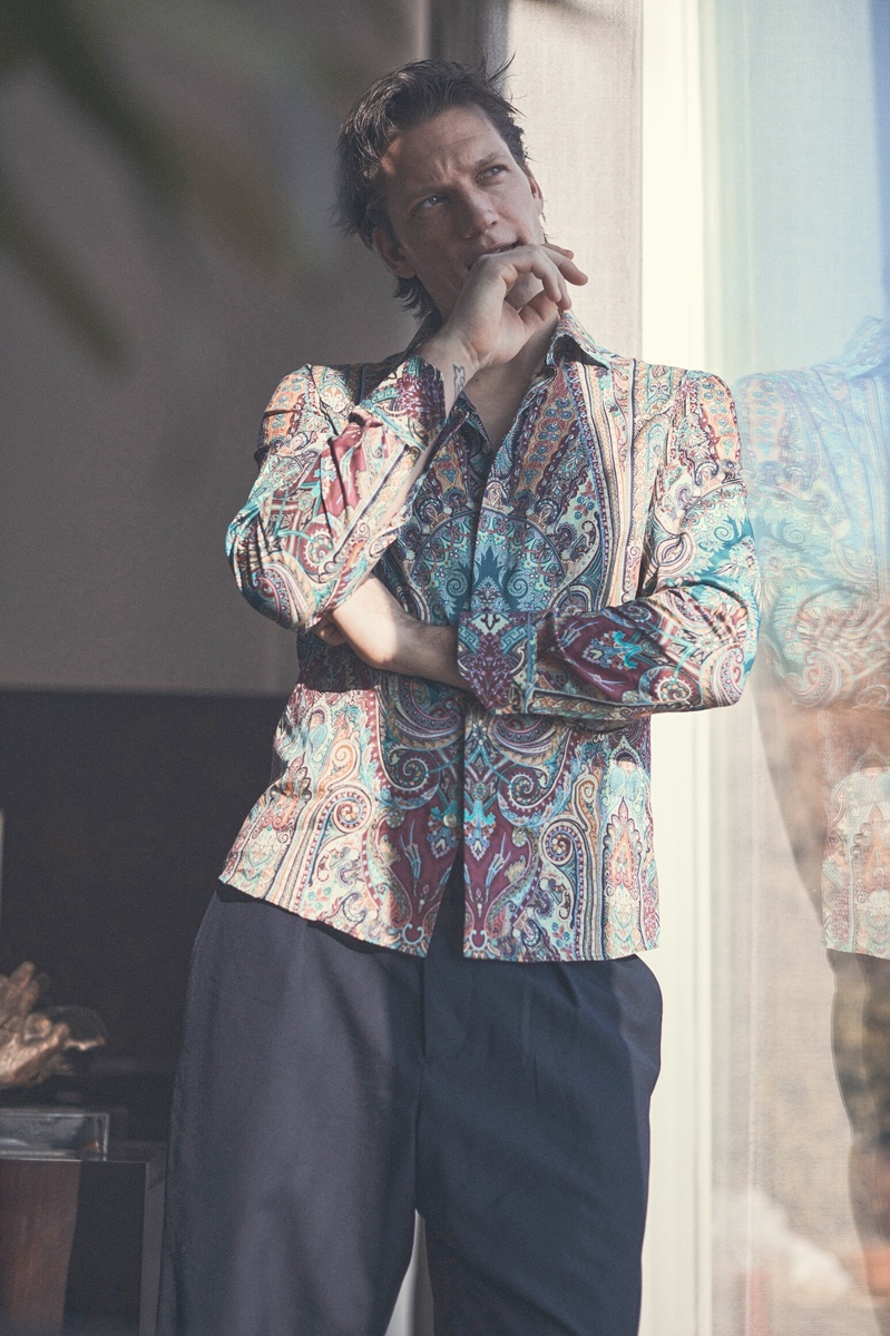 Stealing a calm moment, Florian Van Bael wears a paisley print Etro shirt with Marni trousers for Luisaviaroma.