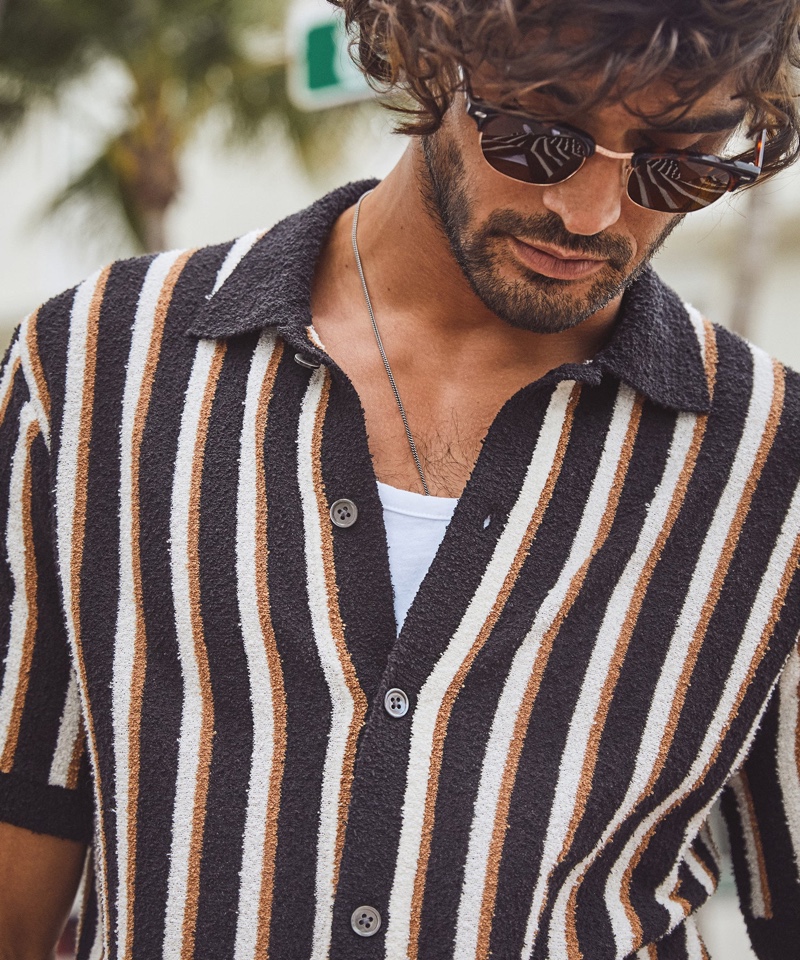 Model Marlon Teixeira wears Todd Snyder's cotton boucle placket vertical stripe sweater polo in black.