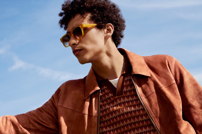 Jackson Hale wears a Mr P. Metis suede blouson jacket, knitted cotton-jacquard polo shirt, organic cotton-jersey t-shirt, and Mr P. + Cubitts Panton square-frame acetate sunglasses.