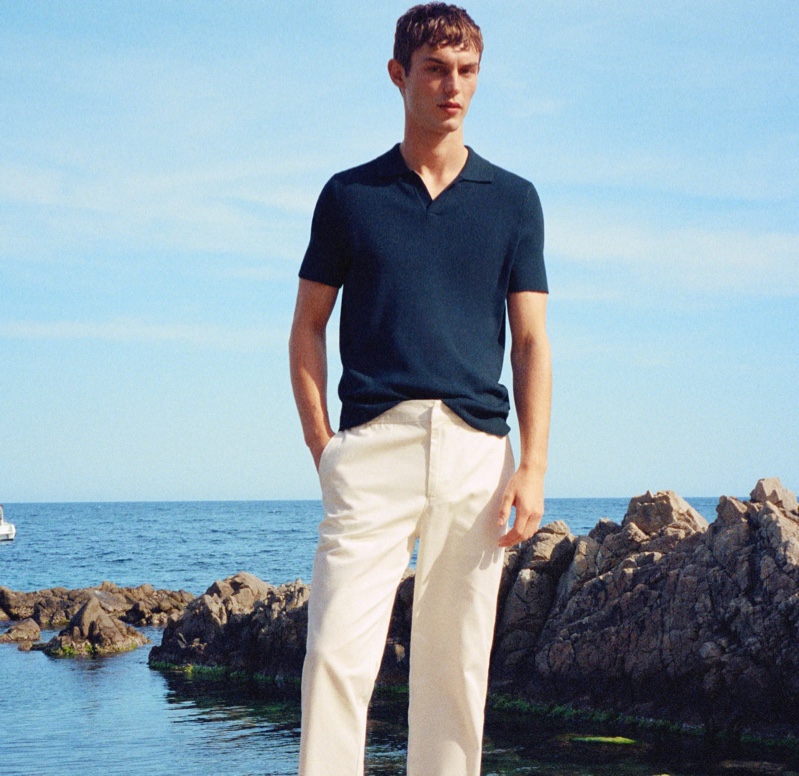 In front and center, Kit Butler models a navy knit polo with white pants from Mango Man.