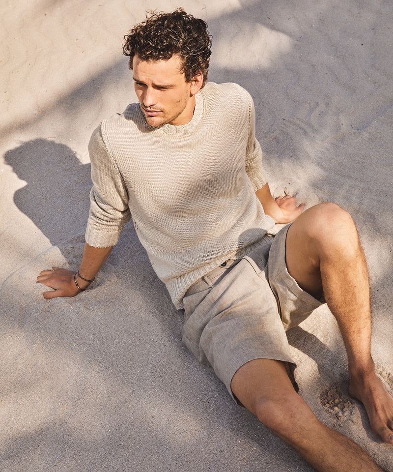 Canadian model Simon Nessman enjoys a day on the beach in Todd Snyder's Italian linen crewneck sweater in khaki. He also wears the brand's 9" Italian Madison linen shorts in khaki.
