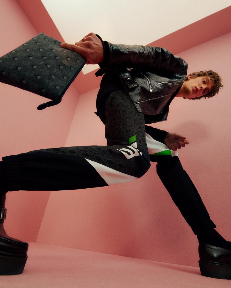 Model Leon Dame poses with the MCM Aren wristlet zip pouch for the brand's fall-winter 2022 campaign.