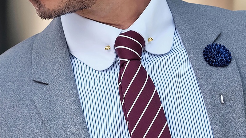 Gold collar pin with a burgundy repp stripe tie from Trendhim