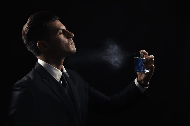 Man Spraying Cologne Black Background