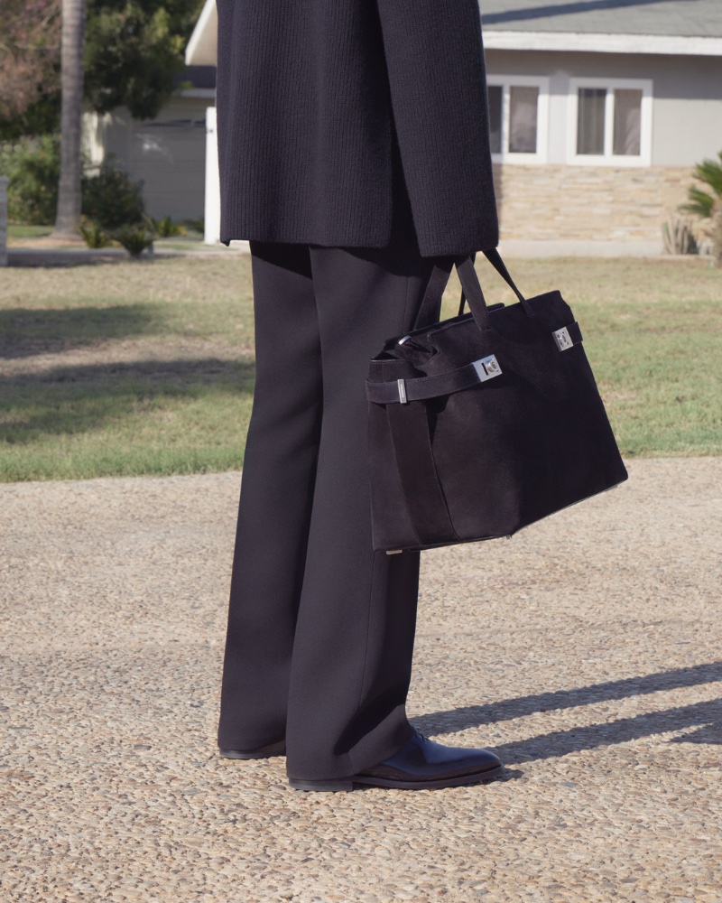 Dressed in black, Diogo Gomes takes hold of a Ferragamo bag for the brand's spring-summer 2023 campaign.