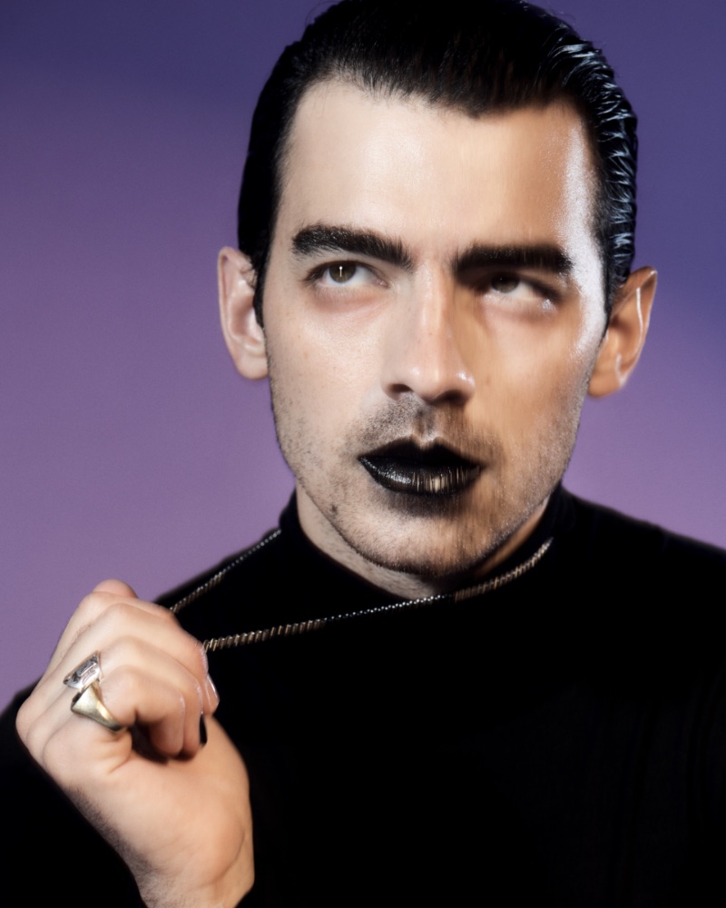 Joe Jonas wears black lipstick and nail polish. A Celine sweater and sterling silver necklace complement his minimal goth look. 