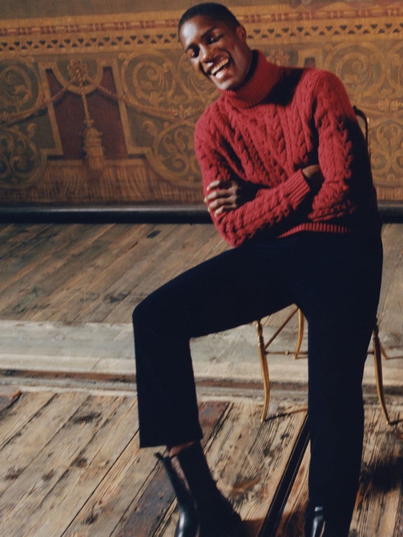All smiles, Mukasa Kakonge charms in a red cable knit turtleneck sweater.