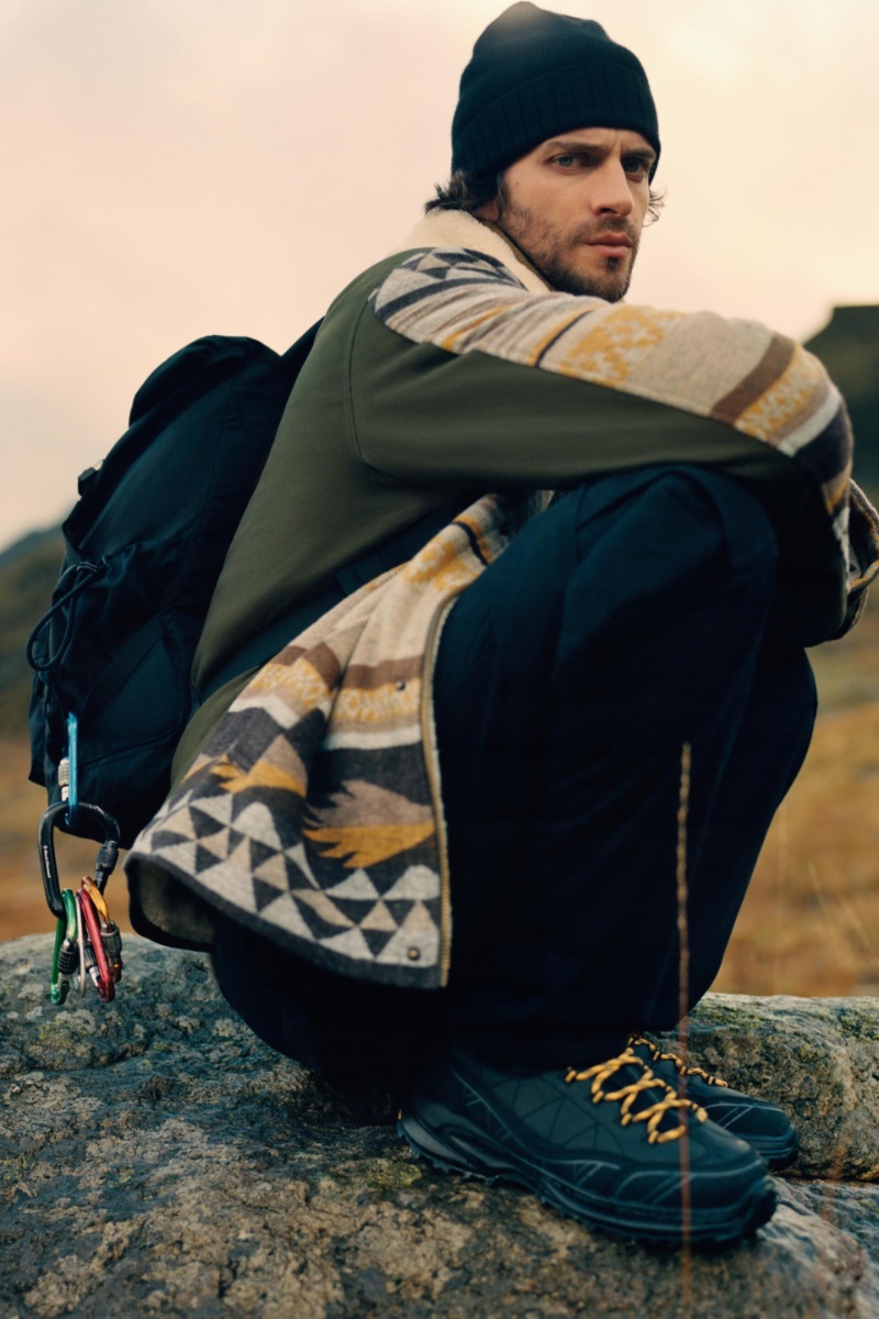 British model Matthew Bell sports a jacquard jacket with trekking high top sneakers, and an explorer backpack. 