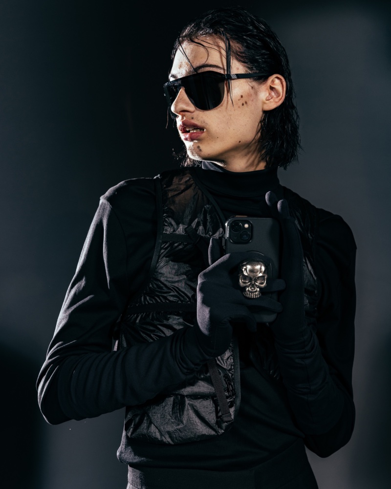 Posing with PopSockets' Heavy Metal skull grip, glaive wears a Moncler x Alyx vest with a Leakier turtleneck and Westward sunglasses.