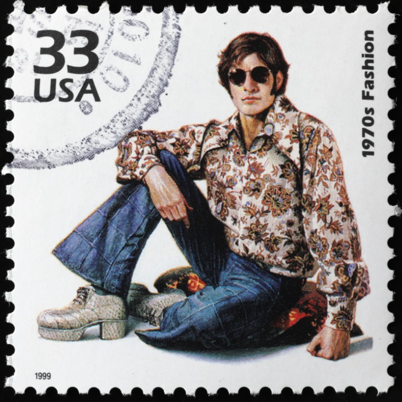1970s fashion stamp featuring man in paisley print shirt with flared jeans and platform shoes.