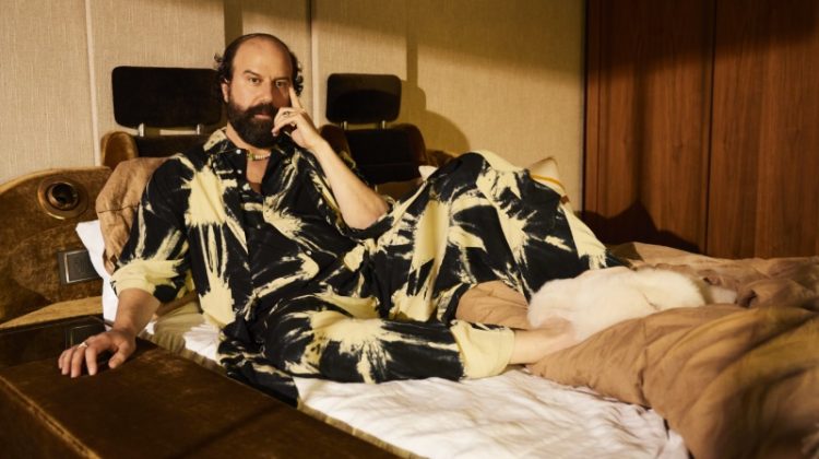 Relaxing in bed, Brett Gelman rocks a SUKU pajama set with Bottega Veneta shearling sandals.