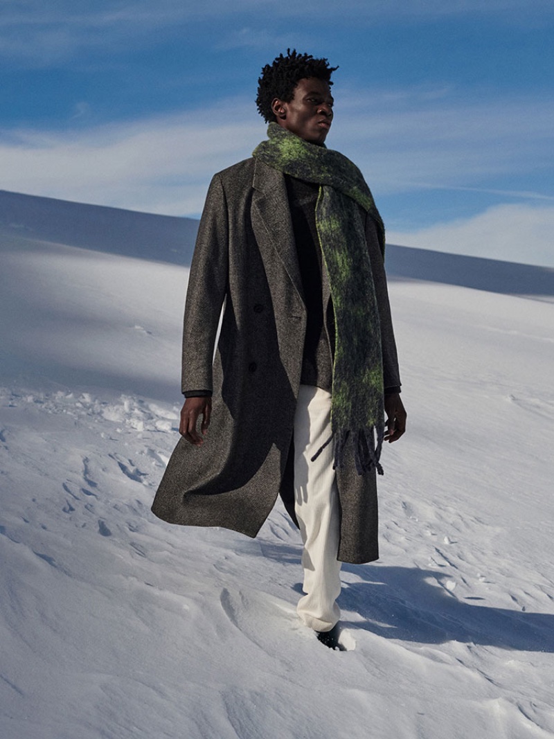Felix Owusu dons a long winter coat with stylish layers.