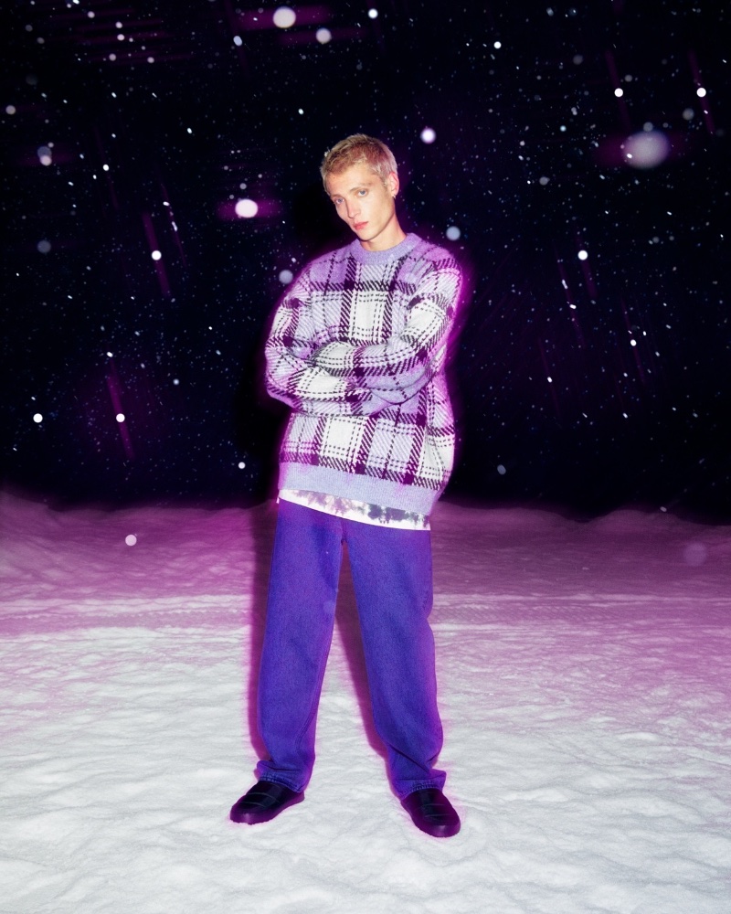 Tom Rey models an oversized fit jacquard-knit sweater with a purple plaid print.