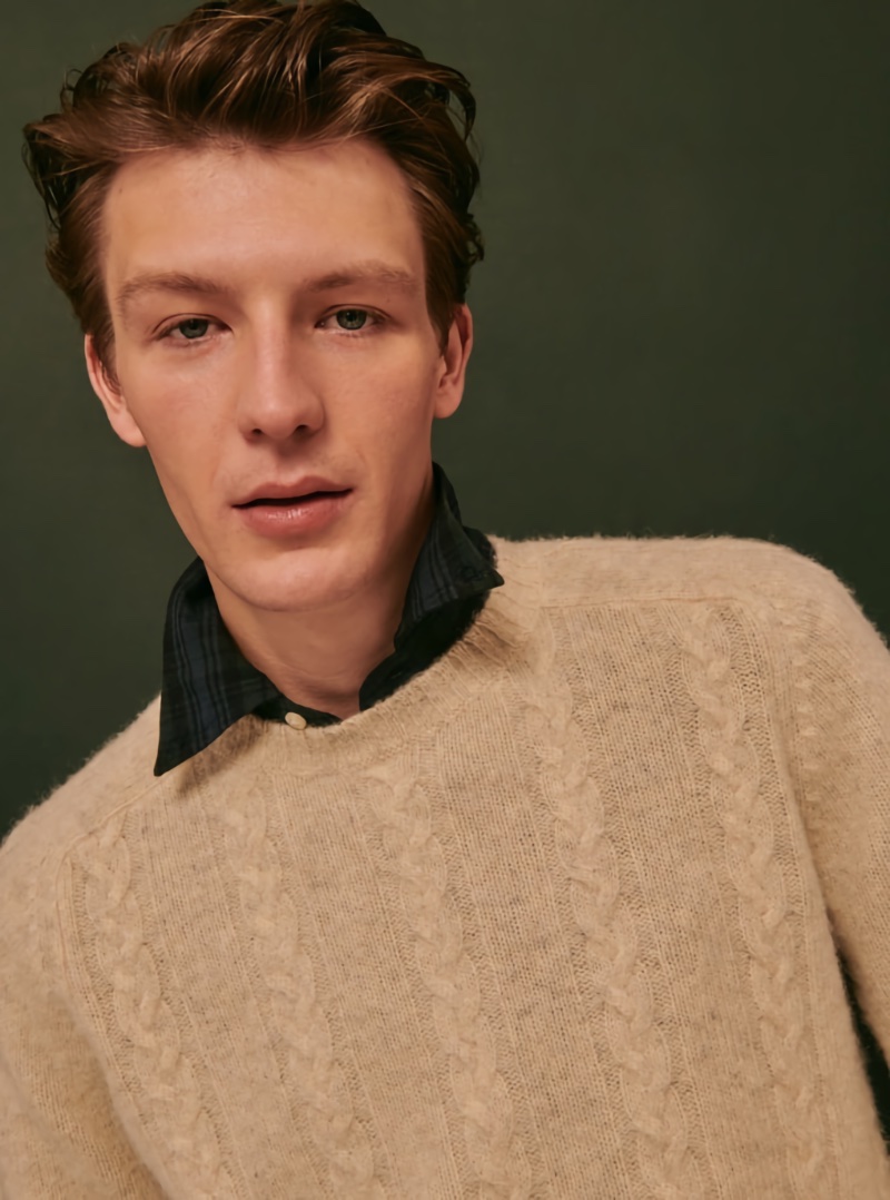 Model Finnlay Davis dons a cable-knit sweater with a button-down shirt. 