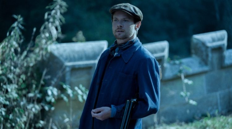 Pictured as Oliver Mellors in Lady Chatterley’s Lover, Jack O'Connell wears a blue chore jacket with a flat cap.
