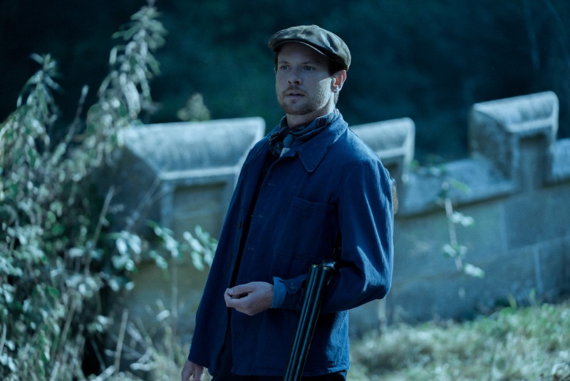 Pictured as Oliver Mellors in Lady Chatterley’s Lover, Jack O'Connell wears a blue chore jacket with a flat cap.