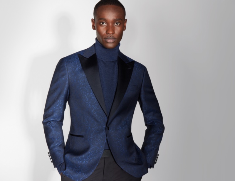 Stunning in blue, Charles Oduro dons a Jack Victor navy paisley dinner jacket with a turtleneck sweater and black wool tuxedo trousers. 