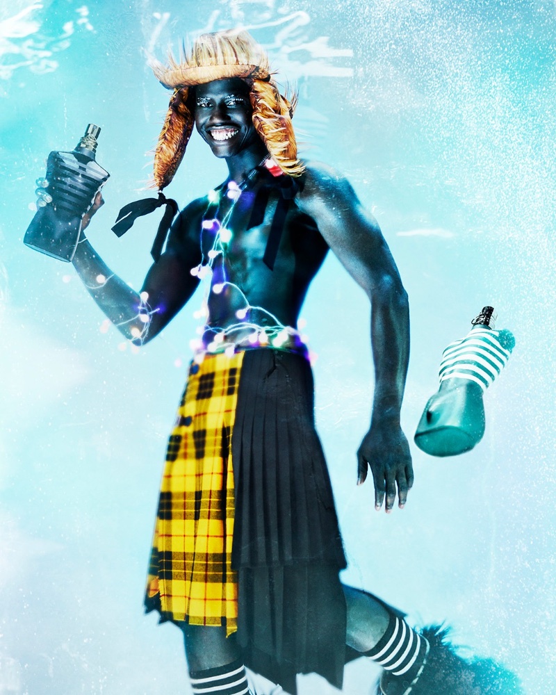 A smiling Omar Sesay poses with Jean Paul Gaultier's famous Le Male fragrance for the brand's holiday 2022 campaign.