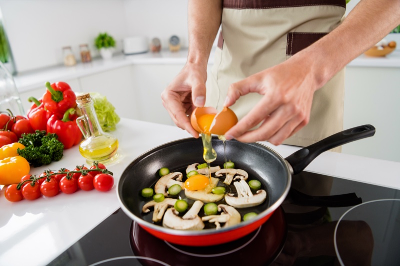 man cooking healthy eggs mushrooms