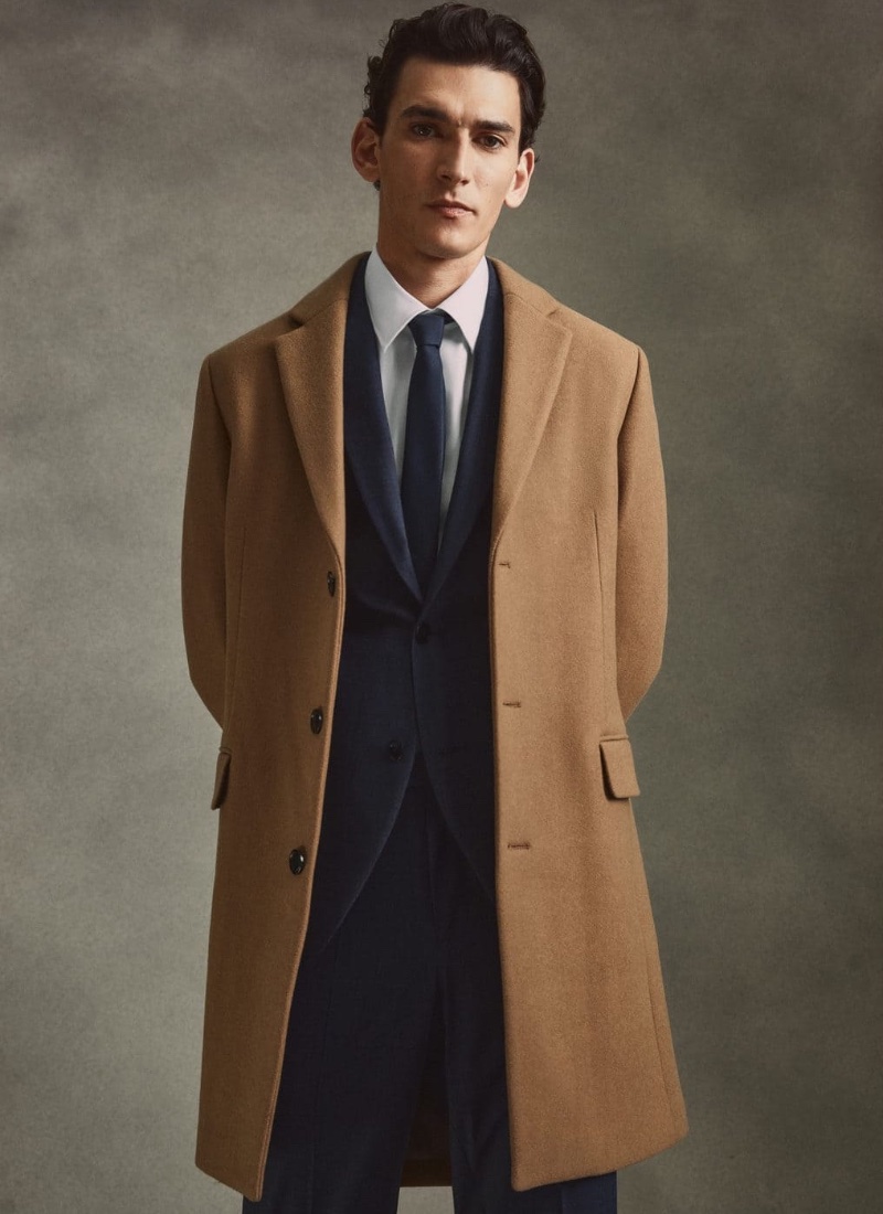 Thibaud Charon dons Mango's camel coat with an elegant suit, shirt, and tie.