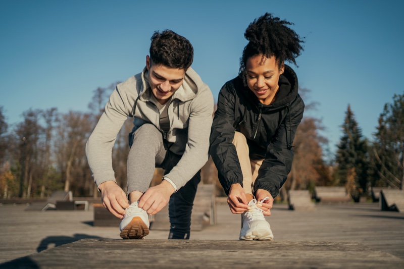 stylish couple work out gear tying sneakers