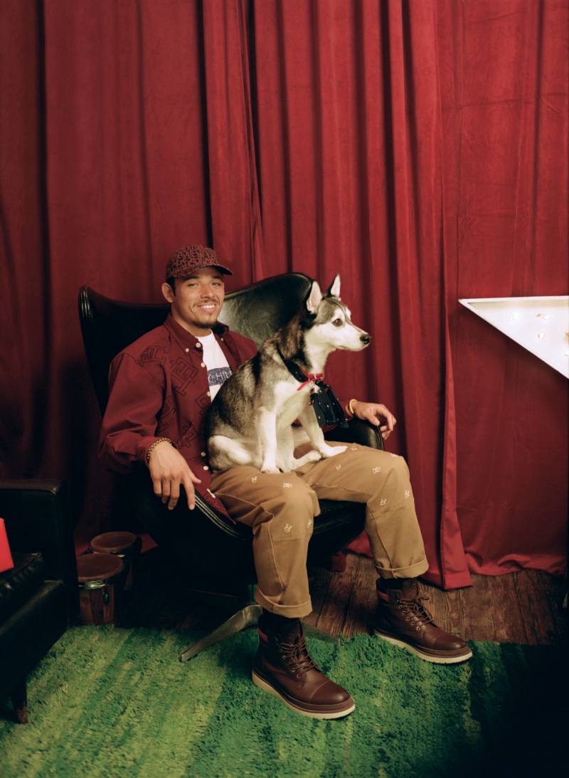 Posing with his dog Prince, Anthony Ramos wears a monogram shirt and chinos from his Tommy Hilfiger holiday 2022 capsule collection.