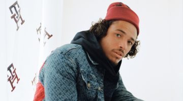 Anthony Ramos wears a monogram denim trucker jacket with velour track pants from his Tommy Hilfiger holiday 2022 capsule collection.