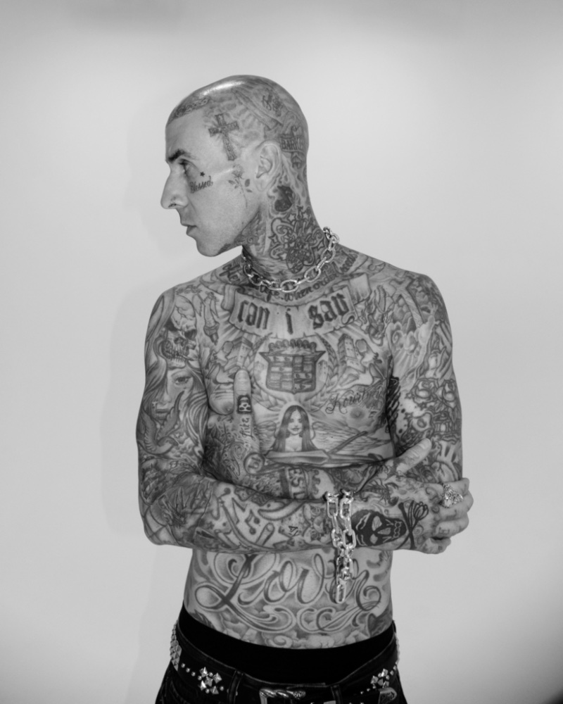 Posing shirtless, Travis Barker not only shows off his body of tattoos but his new jewelry designs for Clocks + Colours.