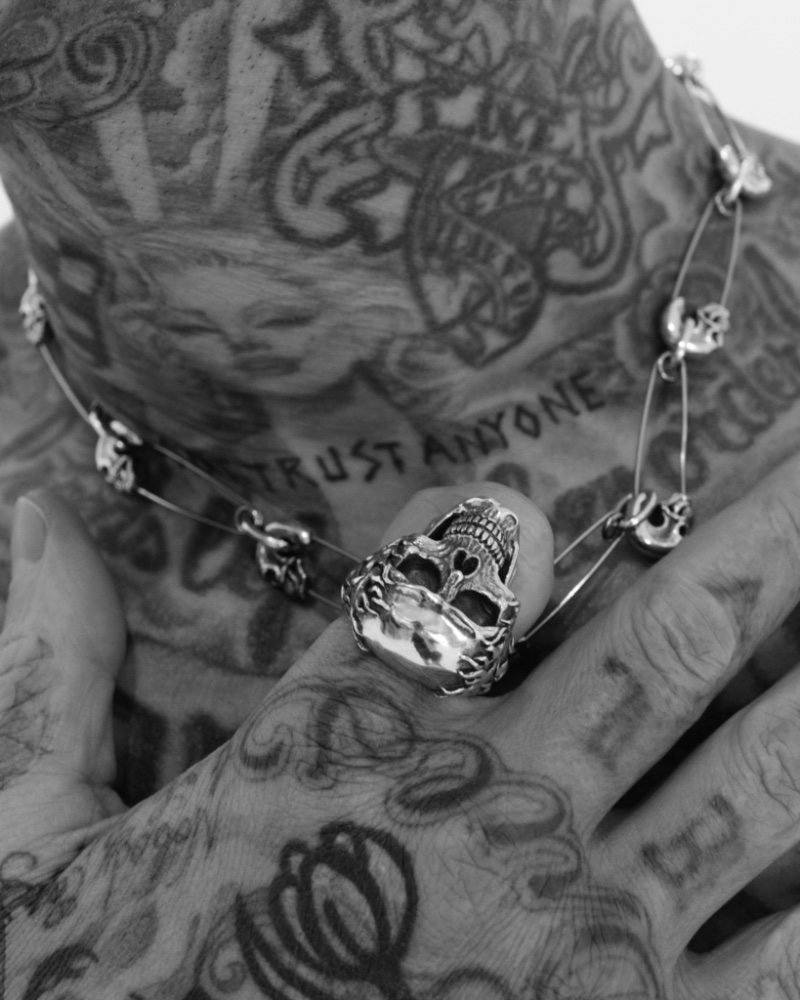 A close-up of Travis Barker shows a skull ring and safety pin-inspired necklace from his first Clocks + Colours drop. 