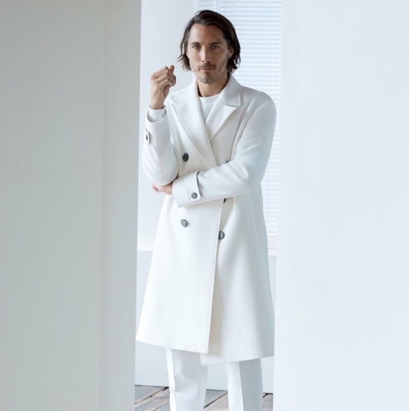 Sporting winter white, Guillaume Macé appears in a Zara double-breasted coat with pleated trousers. 