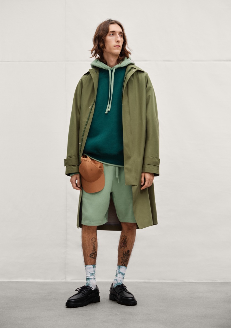 Model Jake Lucas showcases sporty style from H&M in a hoodie, sweatshorts, and an oversized coat.