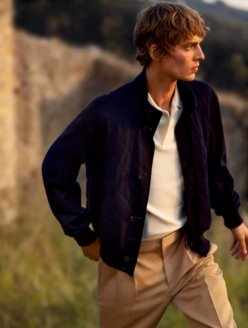 Model Leon Dame is a chic vision in a blue quilted jacket with a white polo and pleated trousers for Loro Piana's spring-summer 2023 campaign.