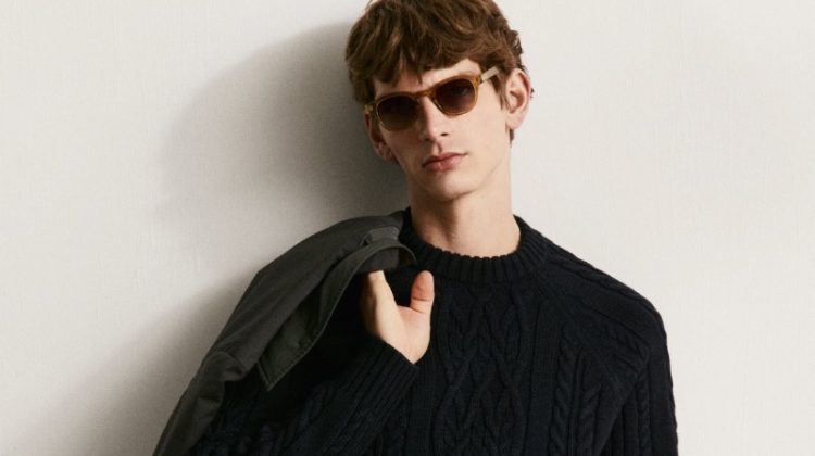 Erik van Gils sports black-on-black in a cable-knit sweater with pleated trousers.