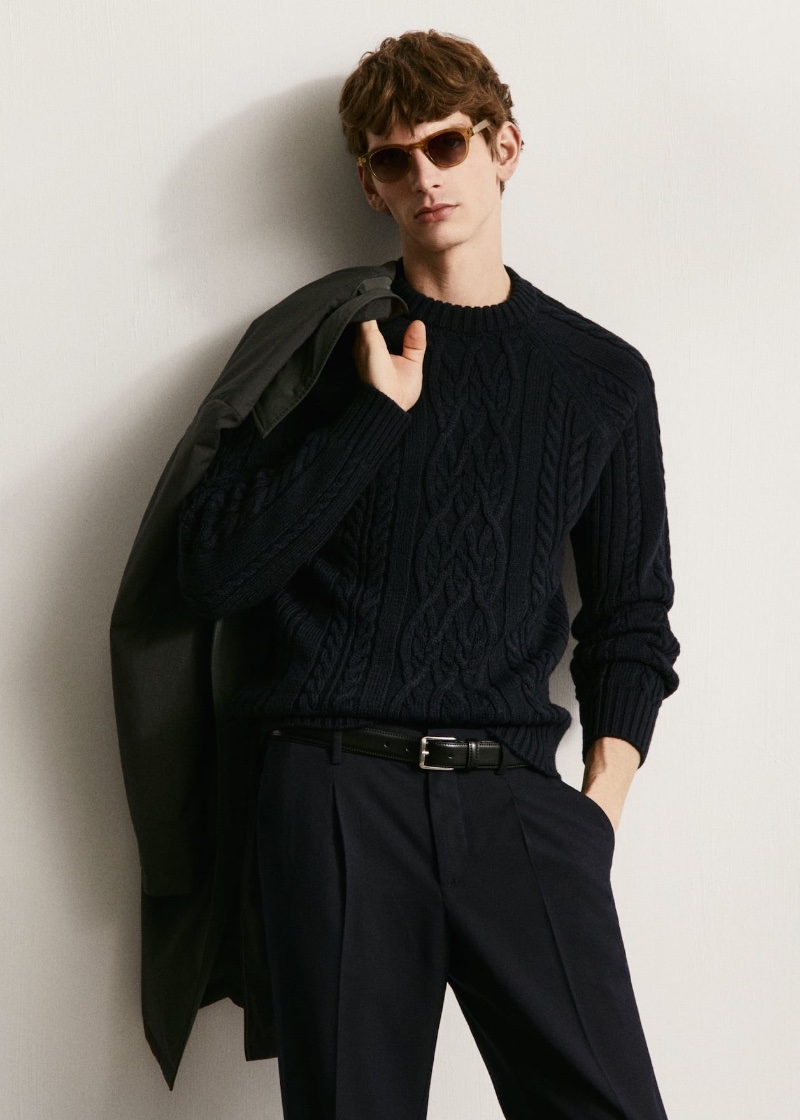 Erik van Gils sports black-on-black in a cable-knit sweater with pleated trousers.
