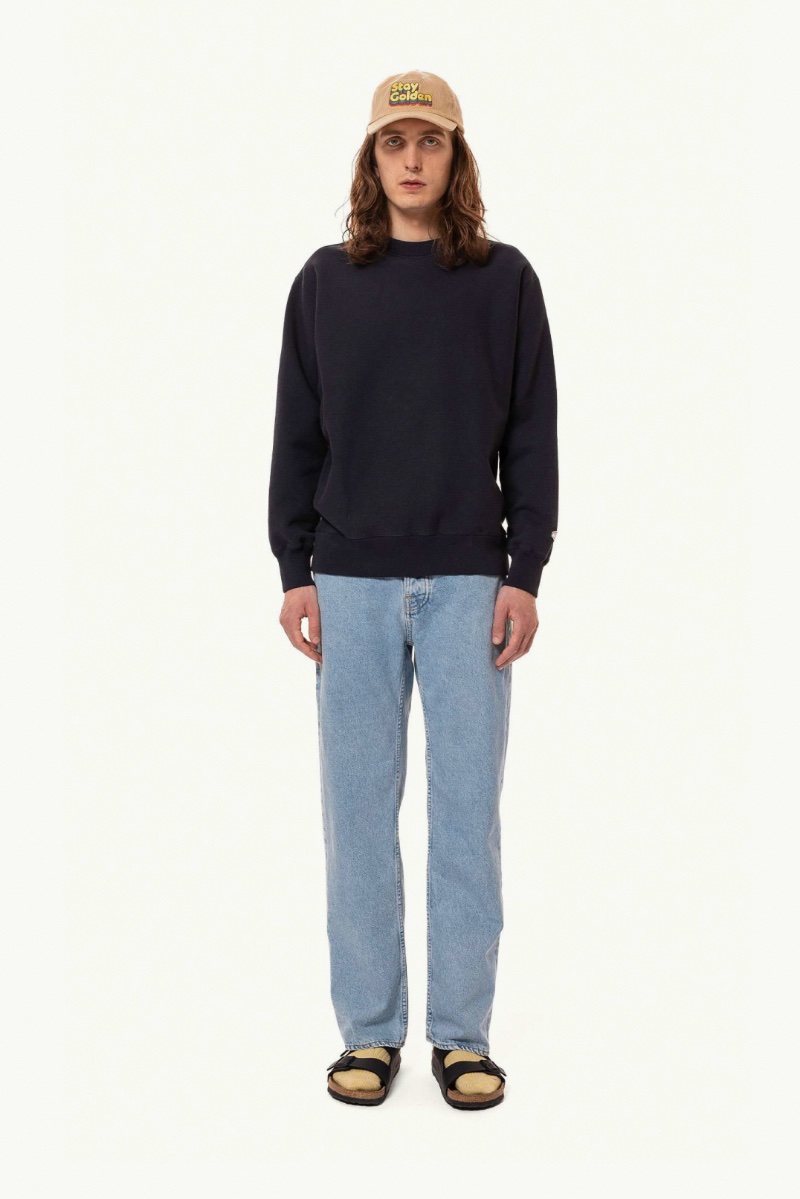 Nudie Jeans captures the simplicity of nineties style with a navy crewneck sweatshirt and its loose-fit Tuff Tony Sunny Blue jeans.