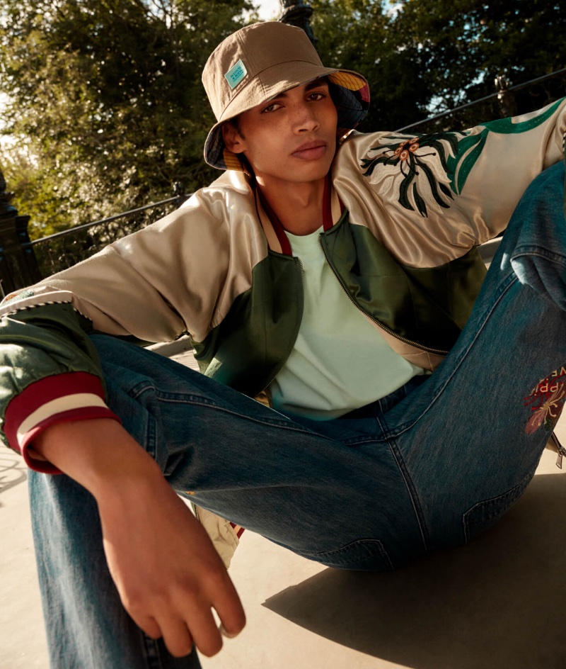 Sol Goss wears a satin bomber with embroidered jeans and a stylish bucket hat.