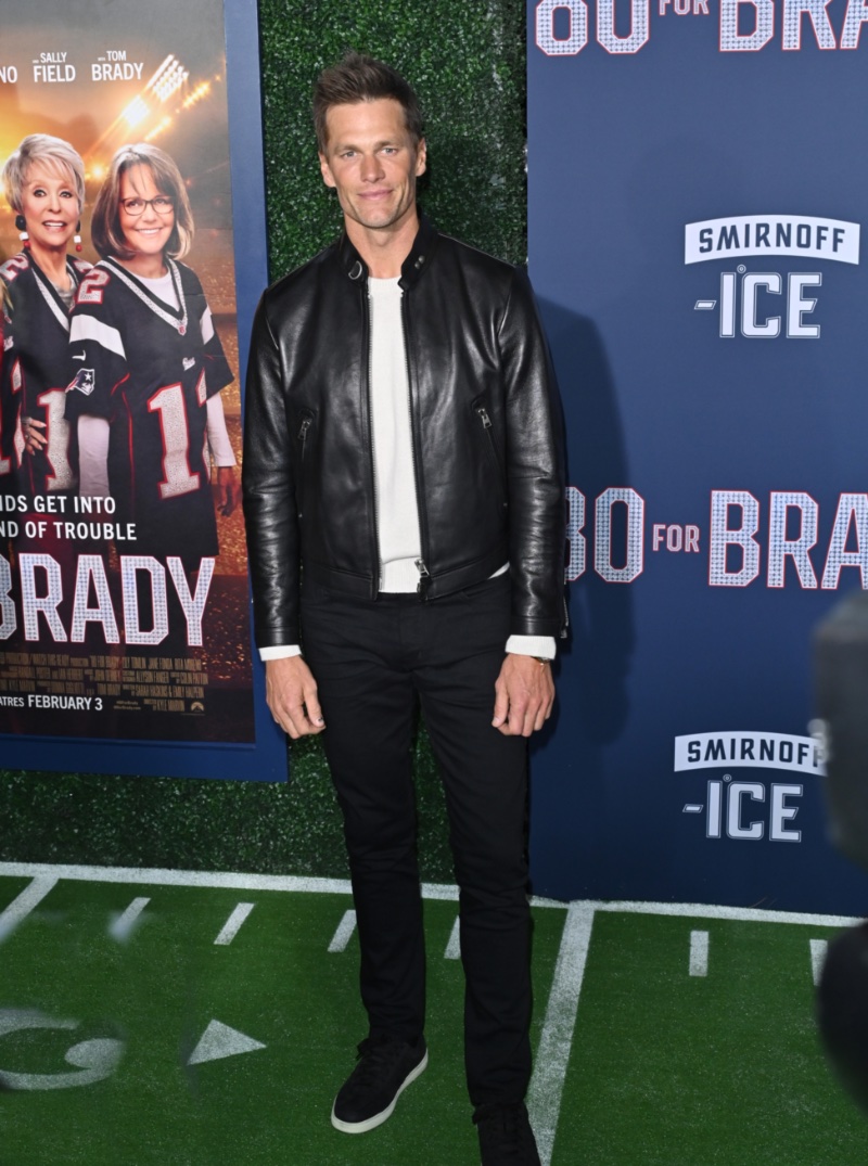 Tom Brady wears a Tom Ford leather jacket, sweater, jeans, and sneakers to the Los Angeles premiere of 80 for Brady.